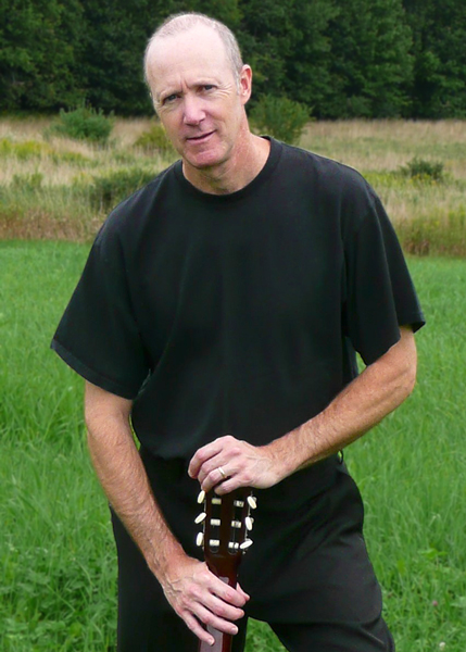 Mark standing in a field with guitar
